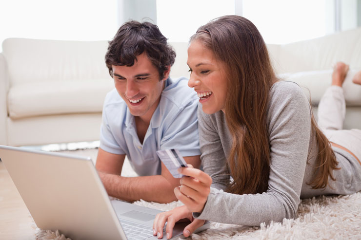Couple lying on the floor with laptop booking holidays