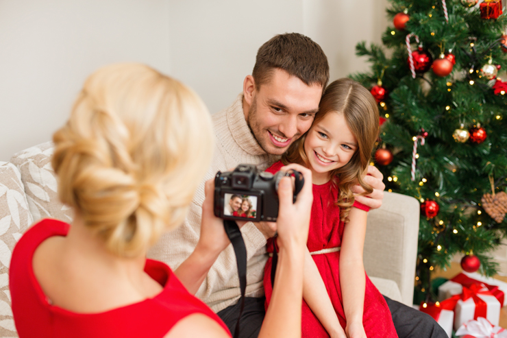 Mother taking picture of smiling father and daughter