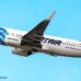 EgyptAir passenger jet in blue and white livery flying against a clear blue sky.